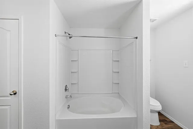 a white bath tub sitting next to a white toilet and vanity