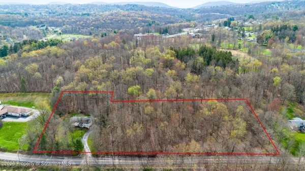 an aerial view of a houses with a lush green forest