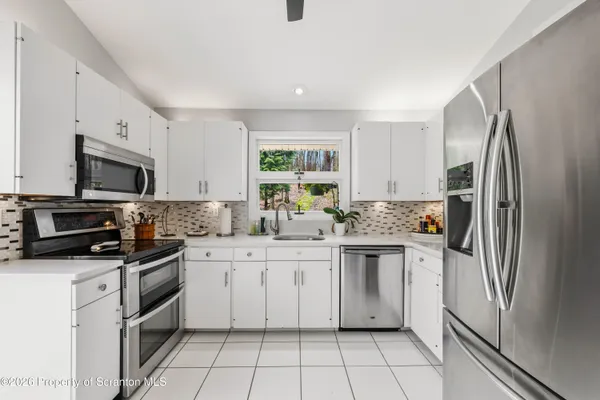 a kitchen with white cabinets stainless steel appliances and a counter space