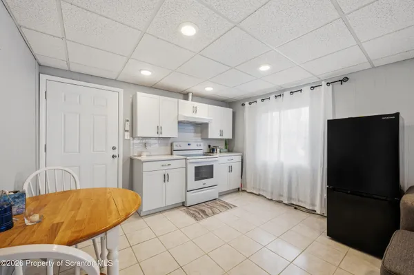 a kitchen with white cabinets and refrigerator