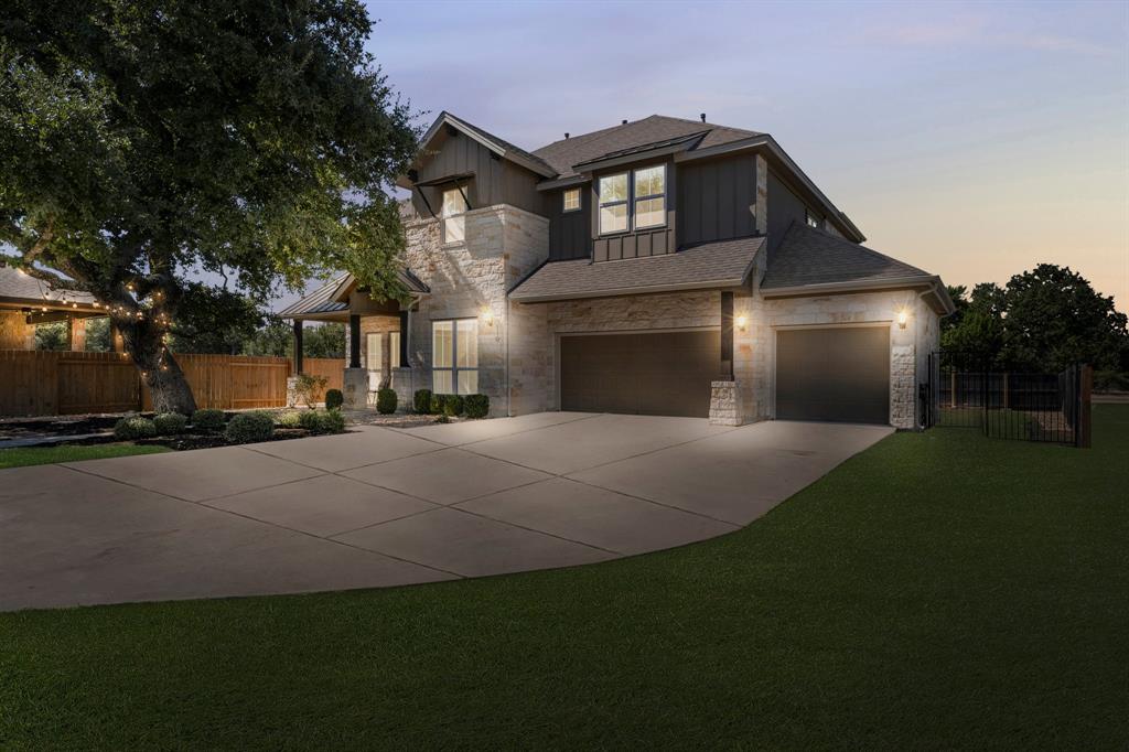 110 Magona Trail Georgetown, TX 78628 - Photo 1 of 38 A grand two-story residence with a stone facade and a large driveway, illuminated for evening appeal.