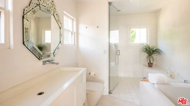 a bathroom with a sink a toilet a mirror and shower