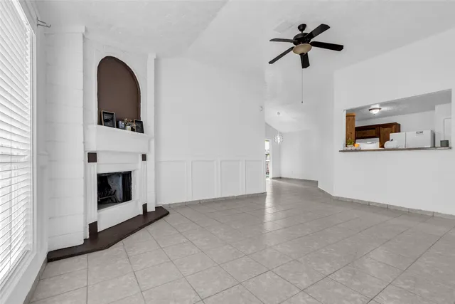 a view of a livingroom with a fireplace a ceiling fan and windows