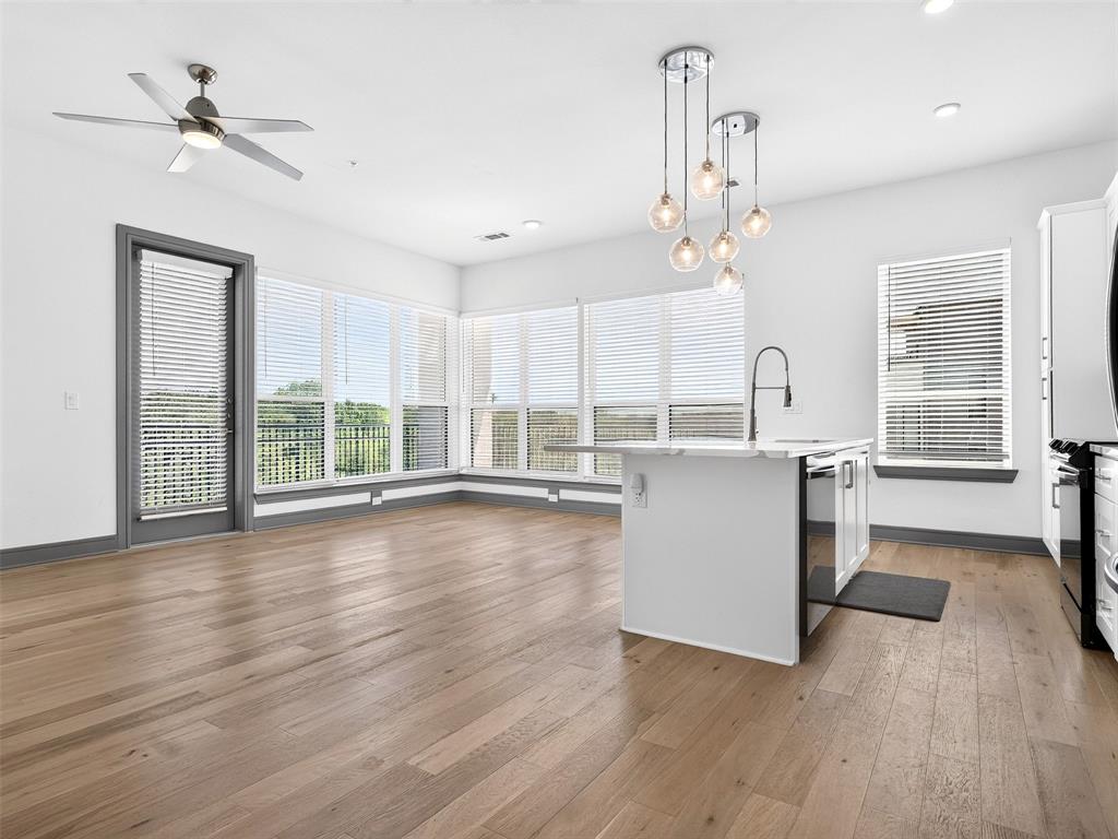Open-concept living area with wood-finish flooring, a contemporary kitchen island, and multiple windows