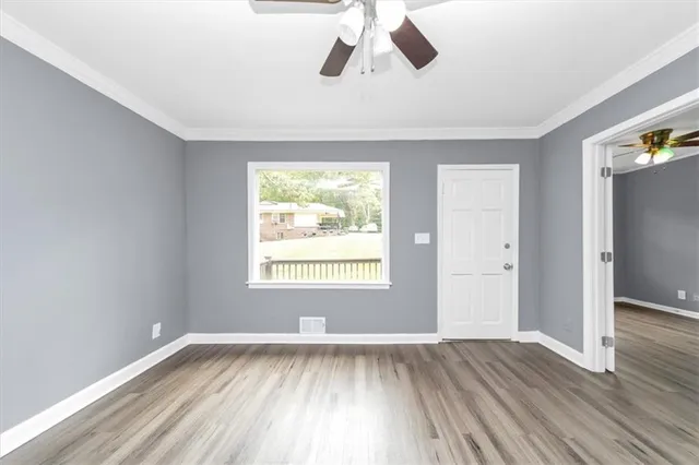 an empty room with wooden floor and windows