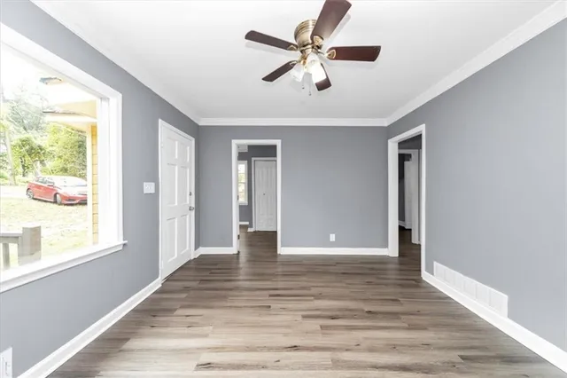 a view of an empty room with wooden floor and a window