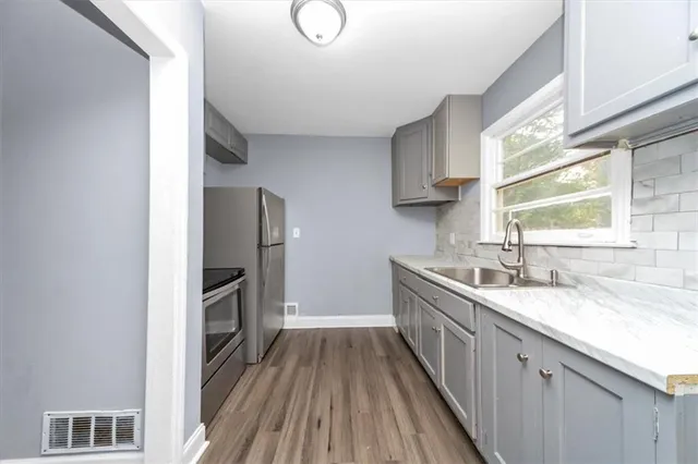 a kitchen with granite countertop a sink stove and refrigerator