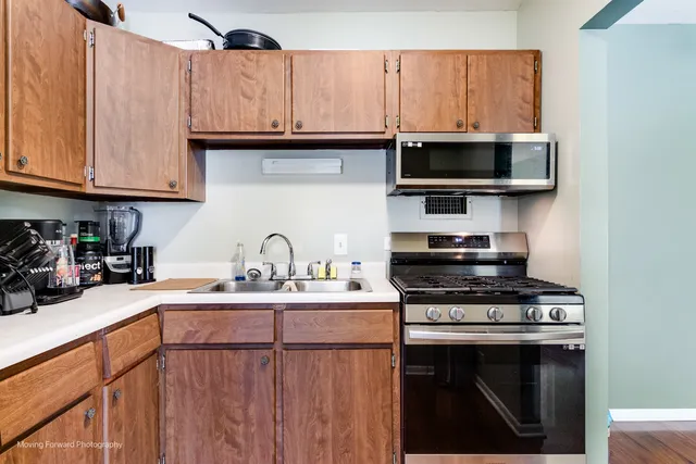 a kitchen with stainless steel appliances granite countertop a refrigerator a sink and white cabinets