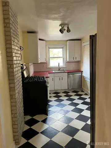 a living room with a black white checkered floor with a gaming machine and dining chairs