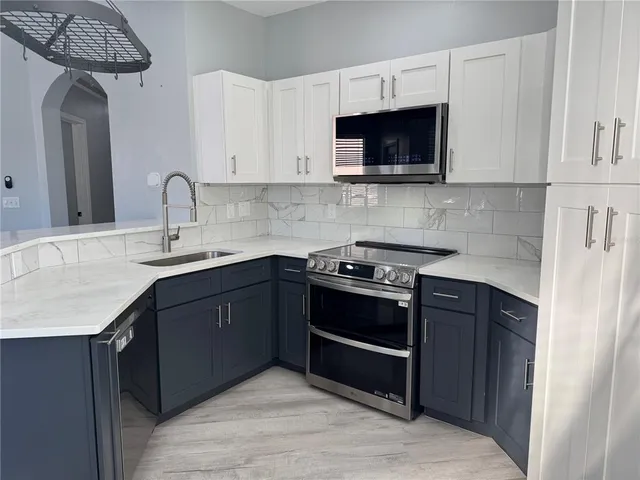 a kitchen with stainless steel appliances granite countertop a stove a sink and a microwave