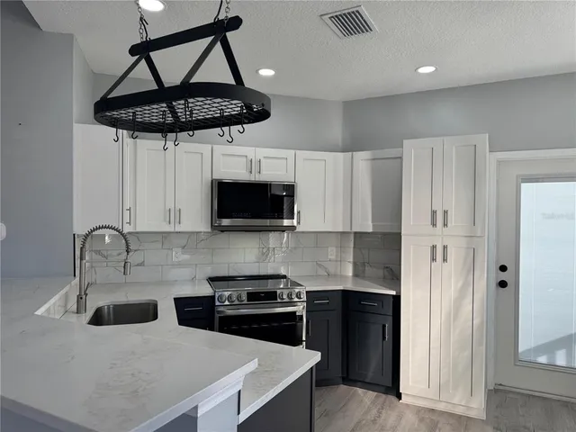 a kitchen with stainless steel appliances a sink a stove a refrigerator and cabinets