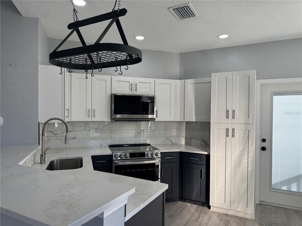 10444 Villa View Circle Tampa, FL 33647 - Photo 3 of 29 a kitchen with stainless steel appliances a sink a stove a refrigerator and cabinets