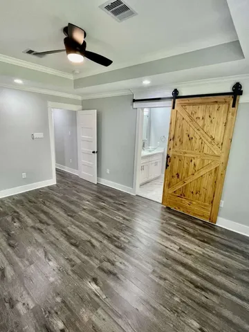 a view of empty room with wooden floor and fan