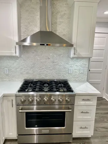 a large kitchen with stainless steel appliances kitchen island granite countertop a table chairs sink and cabinets