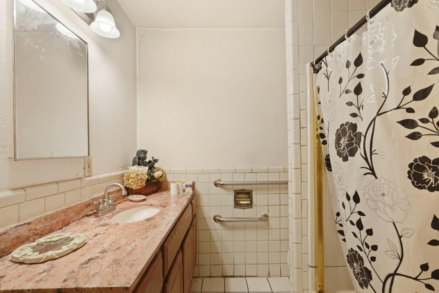 1234 Perry Avenue Stockton, CA 95203 - Photo 18 of 30 a bathroom with a granite countertop sink a mirror and shower curtain
