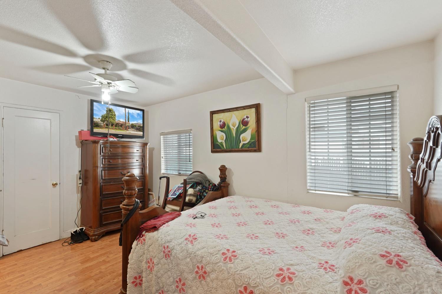 1234 Perry Avenue Stockton, CA 95203 - Photo 22 of 30 a bedroom with a bed a dresser and a chandelier