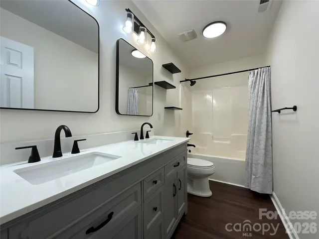 a bathroom with a double vanity sink toilet mirror and shower