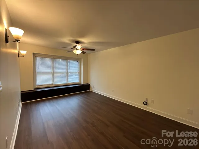 an empty room with wooden floor fan and windows