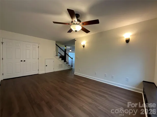 an empty room with wooden floor fan and windows