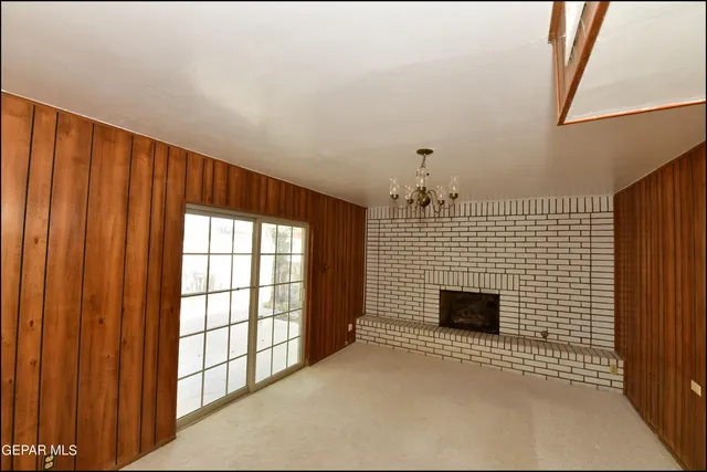 a view of a refrigerator in kitchen and an empty room with wooden floor