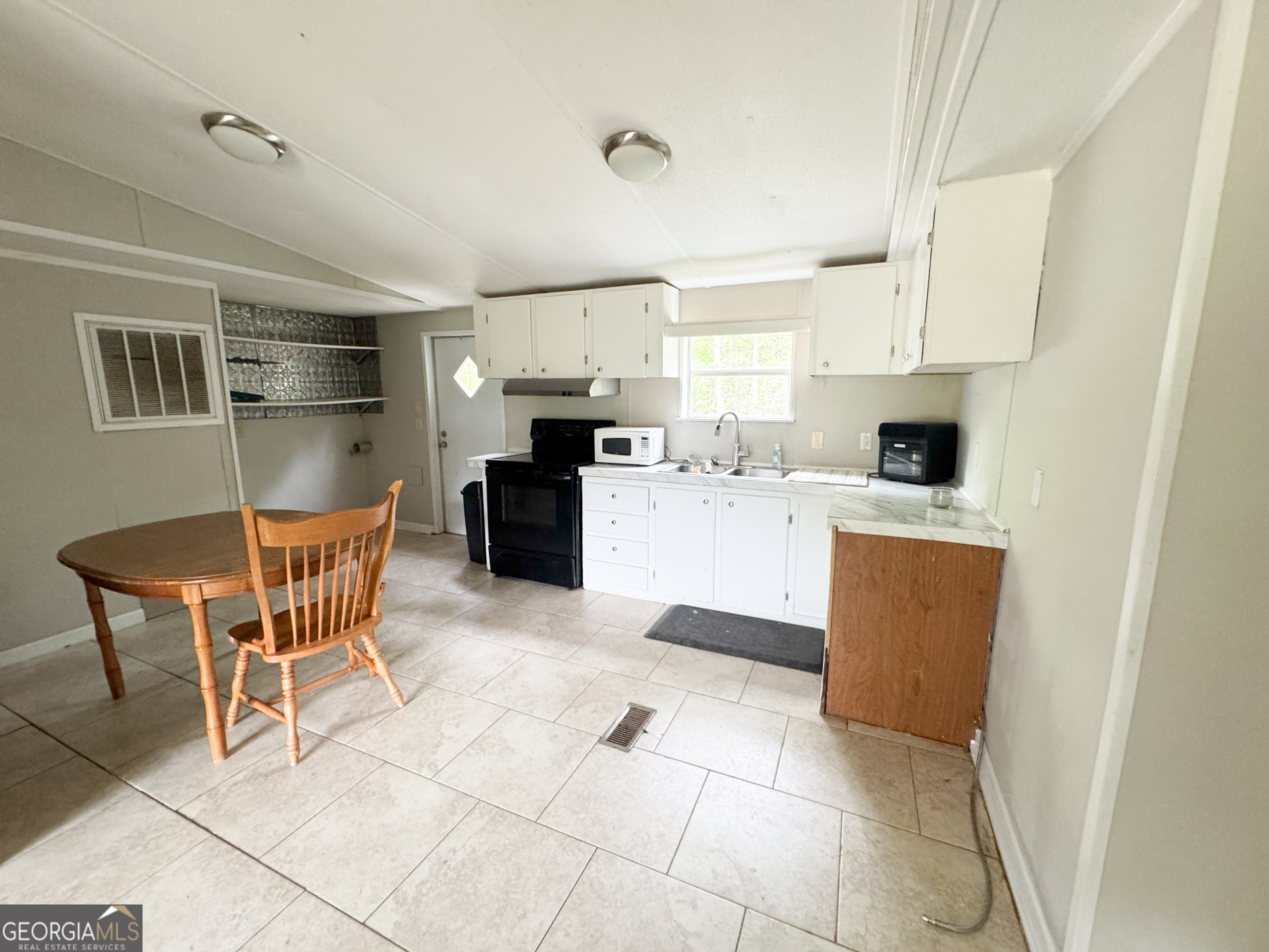 877 West Rushing Road Register, GA 30452 - Photo 10 of 18 a kitchen with stainless steel appliances granite countertop a stove top oven a sink a dining table and chairs