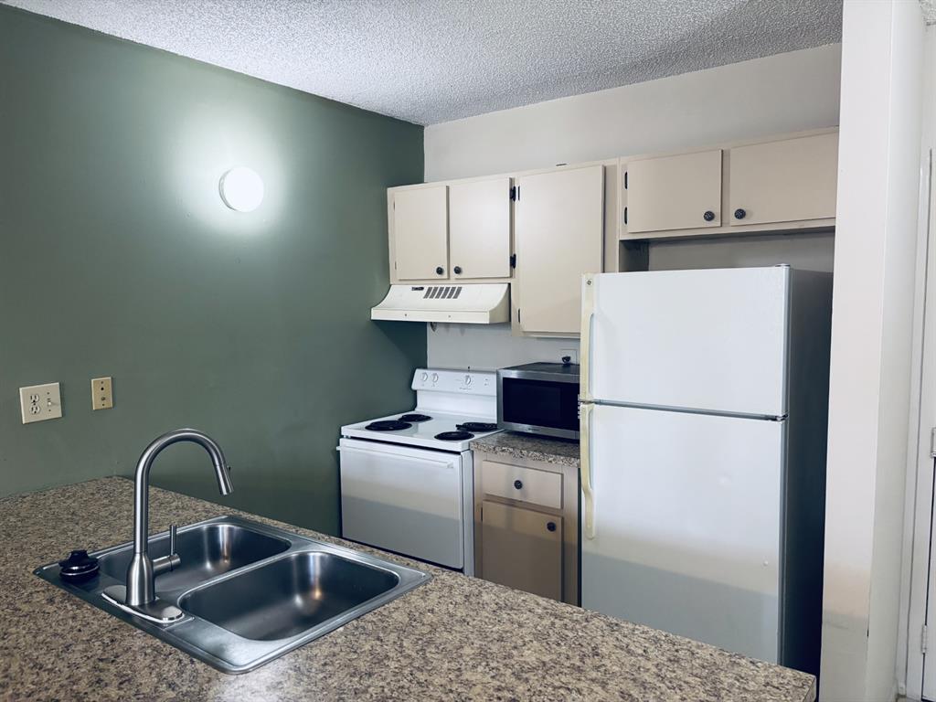 2401 Riverside Drive, Unit 311B Coral Springs, FL 33065 - Photo 3 of 12 a kitchen with a sink a refrigerator and cabinets