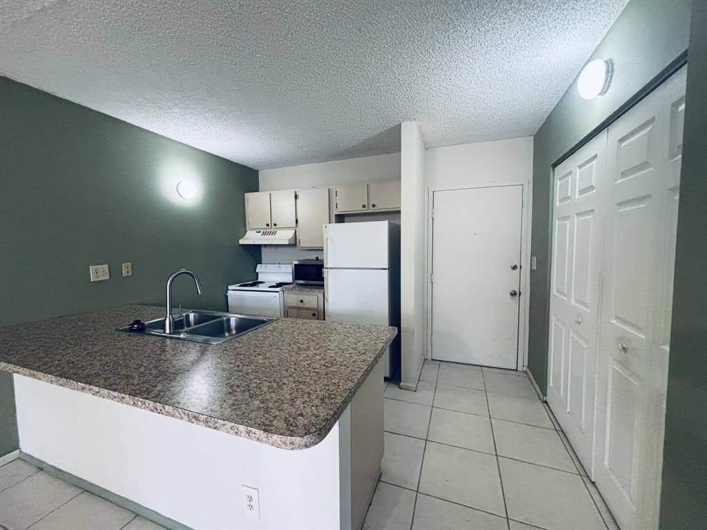 2401 Riverside Drive, Unit 311B Coral Springs, FL 33065 - Photo 4 of 12 a kitchen with kitchen island granite countertop a refrigerator a sink and dishwasher