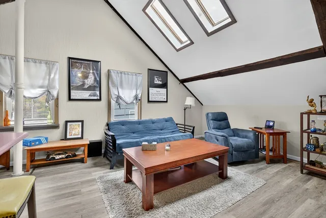 a living room with stainless steel appliances furniture a rug and a kitchen view