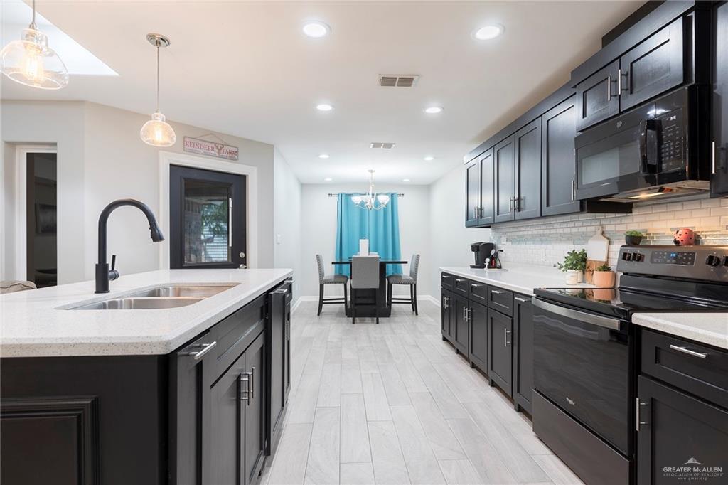 503 Northern Dancer Avenue Edinburg, TX 78539 - Photo 2 of 34 a kitchen with stainless steel appliances kitchen island granite countertop a stove top oven a sink a dining table and chairs with wooden floor