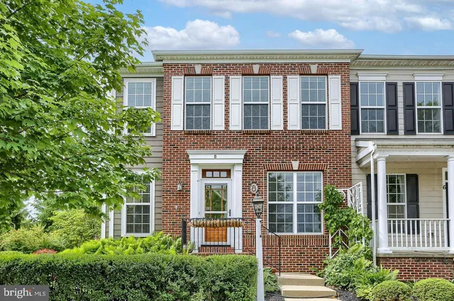 front view of a brick house with large windows and a large tree