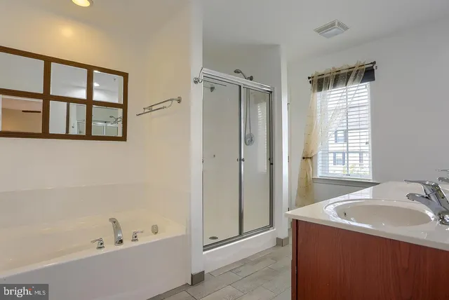 a bathroom with a tub sink shower and mirror