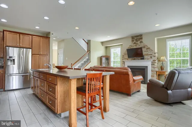 a kitchen with stainless steel appliances granite countertop a stove a sink a refrigerator and a couch