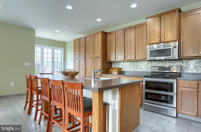 a kitchen with stainless steel appliances a stove a sink a microwave a refrigerator and cabinets