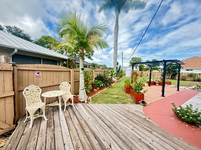 a view of a white house with a big yard and potted plants