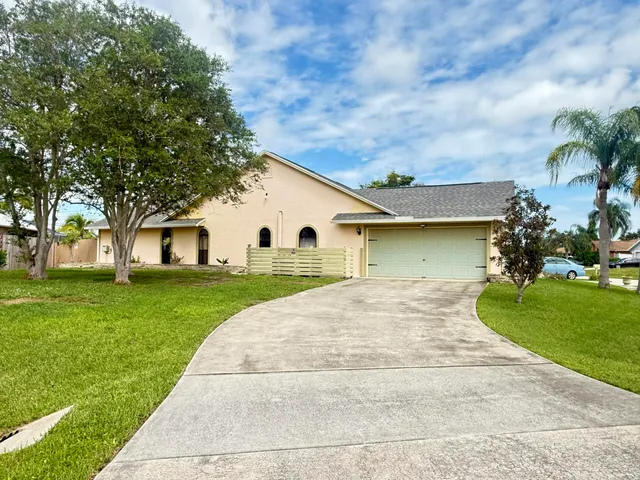 a view of a house with a big yard and large trees