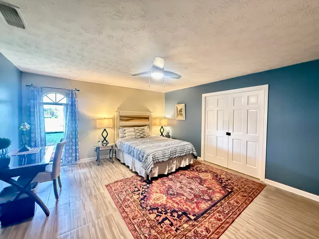 a spacious bedroom with a bed a table and large window with wooden floor