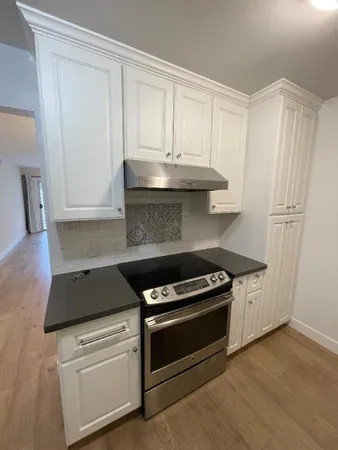 a kitchen with granite countertop white cabinets and black appliances