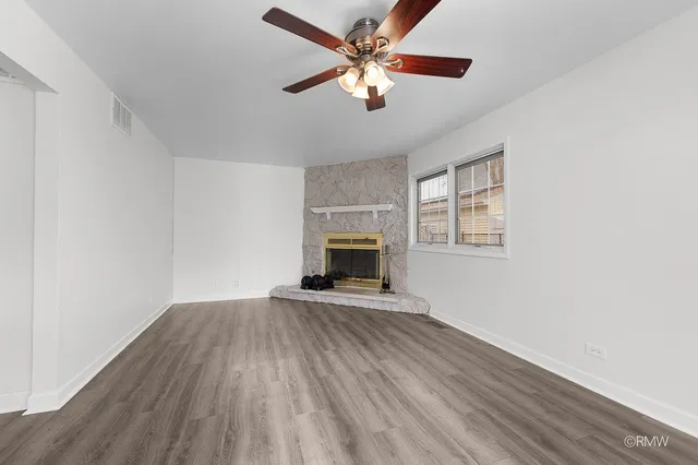 an empty room with windows and fireplace