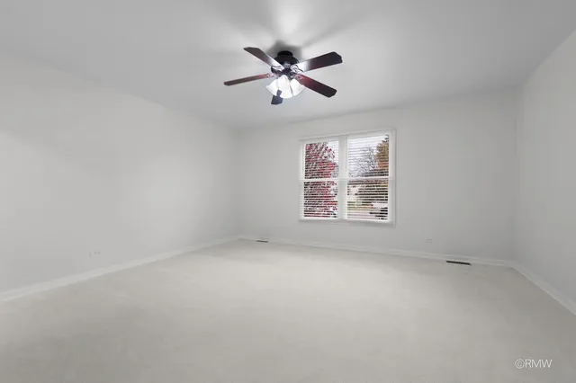 an empty room with windows and fan