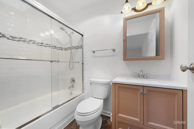 a bathroom with a granite countertop sink a toilet and shower