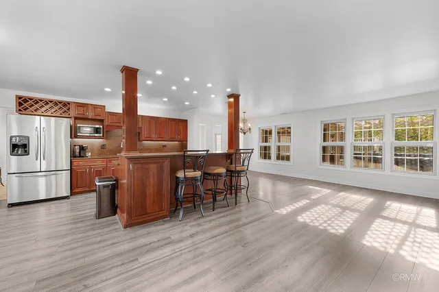 a kitchen with stainless steel appliances a dining table chairs stove and refrigerator