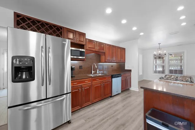 a kitchen with stainless steel appliances granite countertop a refrigerator a stove a sink dishwasher a oven with wooden floor and cabinets