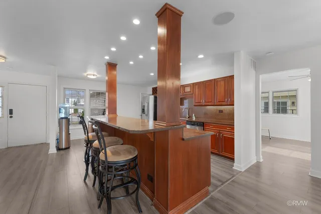 a kitchen with stainless steel appliances kitchen island granite countertop a table chairs and a refrigerator