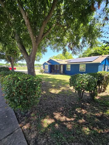a view of a house with a yard and a large tree