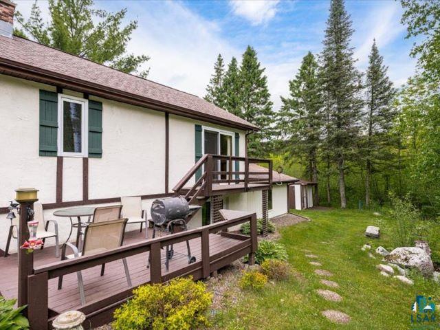 3616 Lavaque Road Hermantown, MN 55811 - Photo 21 of 43 Rear exterior featuring a multi-level wood deck, white stucco siding with dark wood trim, and a shingle roof