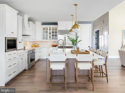a kitchen with white cabinets and wooden floor