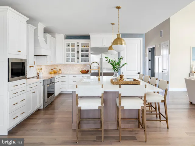 a kitchen with white cabinets and wooden floor