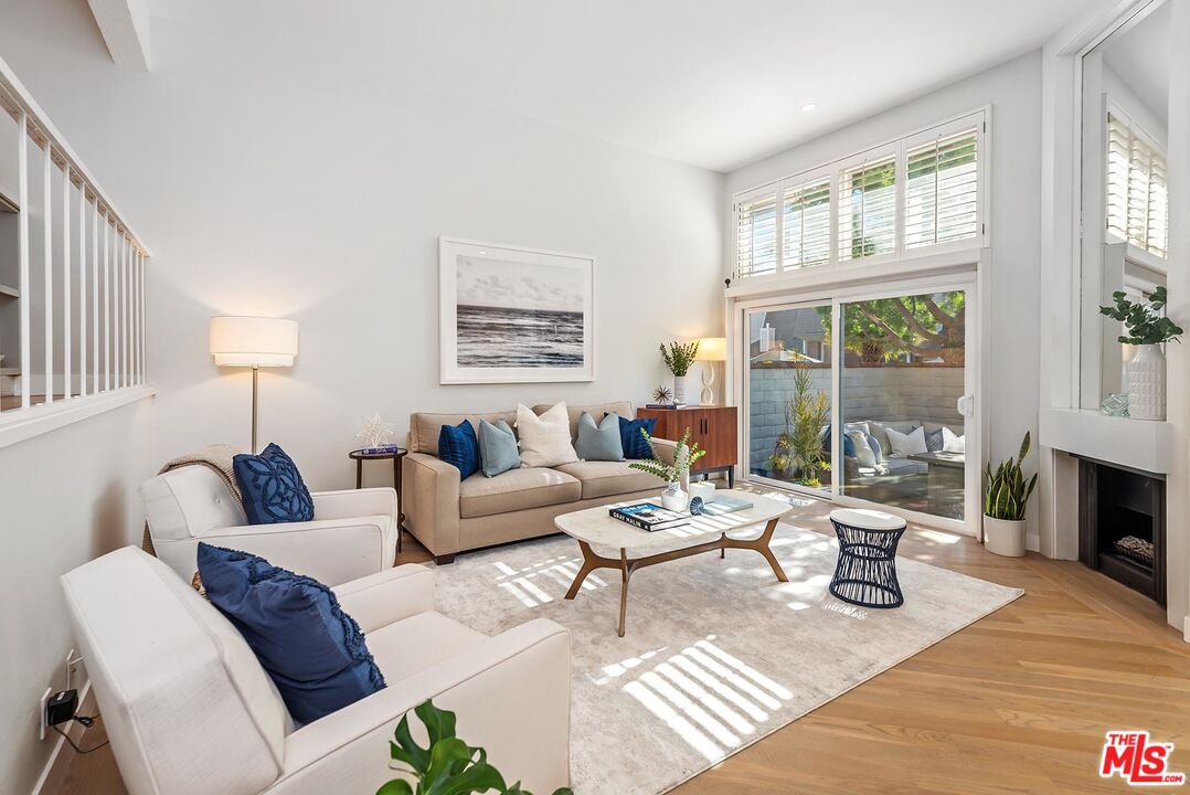 a living room with furniture large window and wooden floor