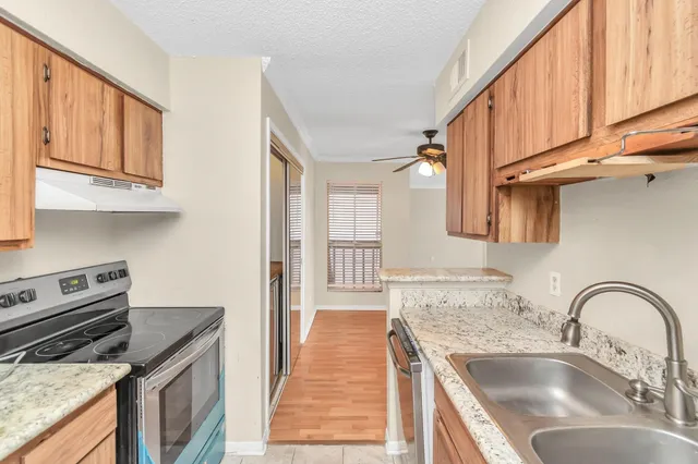 a kitchen with granite countertop a sink a stove and cabinets