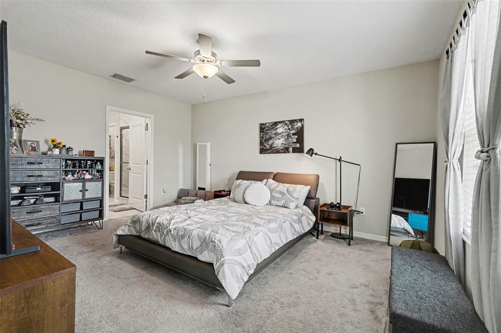 9424 Lemon Drop Loop Sun City Center, FL 33573 - Photo 13 of 31 a bedroom with a bed a couch and chandelier